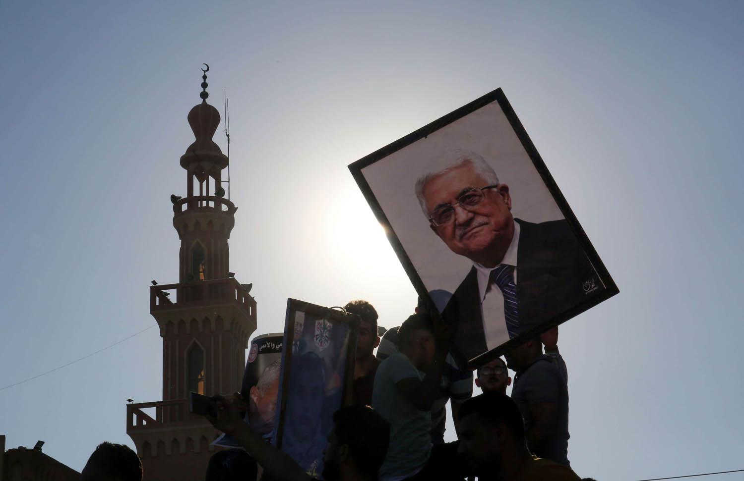 فلسطينيون يرفعون صورة الرئيس الفلسطيني محمود عباس