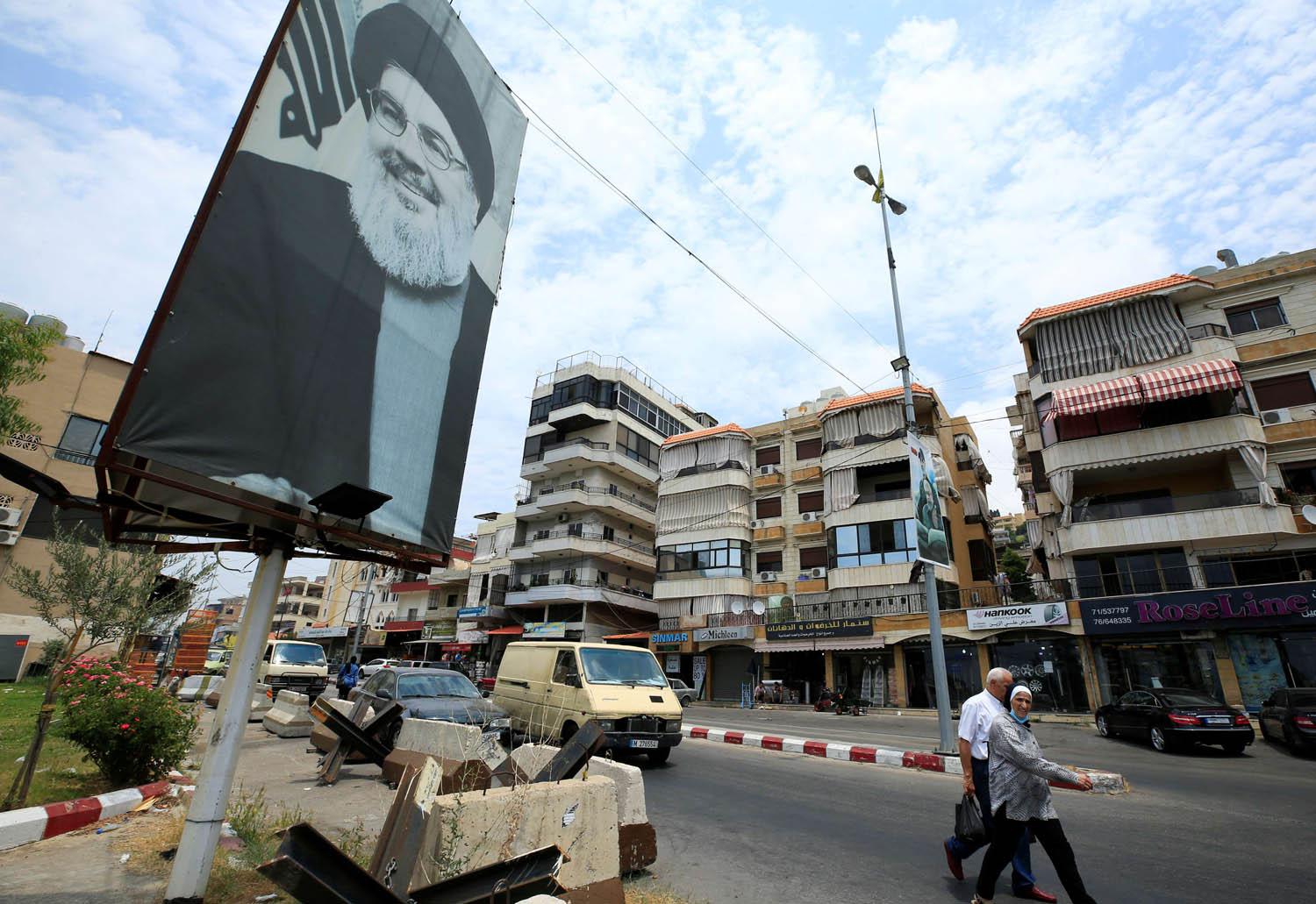 لبنانيون يمرون بجانب ملصق لحسن نصرالله