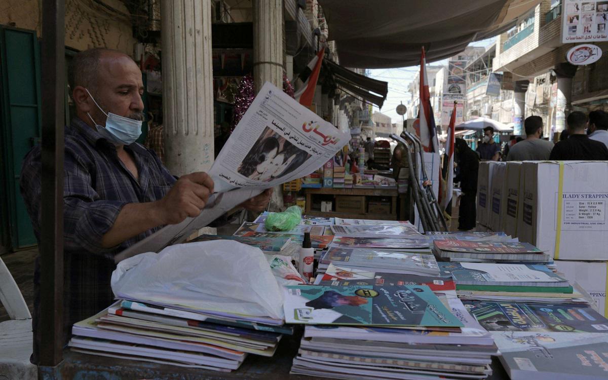 رجل يقرأ صحيفة أمام كشك لبيع للكتب في شارع المتنبي ببغداد