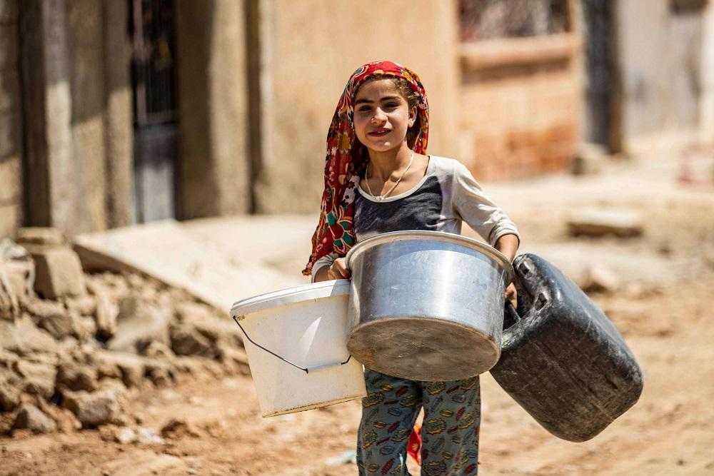 فتاة سورية تندفع لملء الماء من صهاريج قدمتها المنظمات الإنسانية