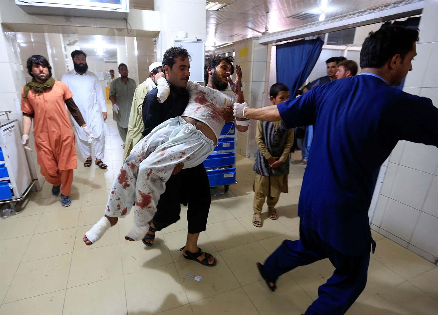 A man carries an injured person in a hospital after blasts, in Jalalabad