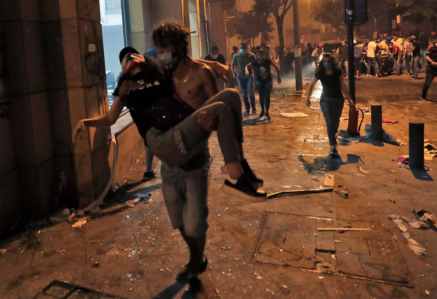 A Lebanese protester carries a wounded demonstrators to safety at the headquarters of the Lebanese association of banks 