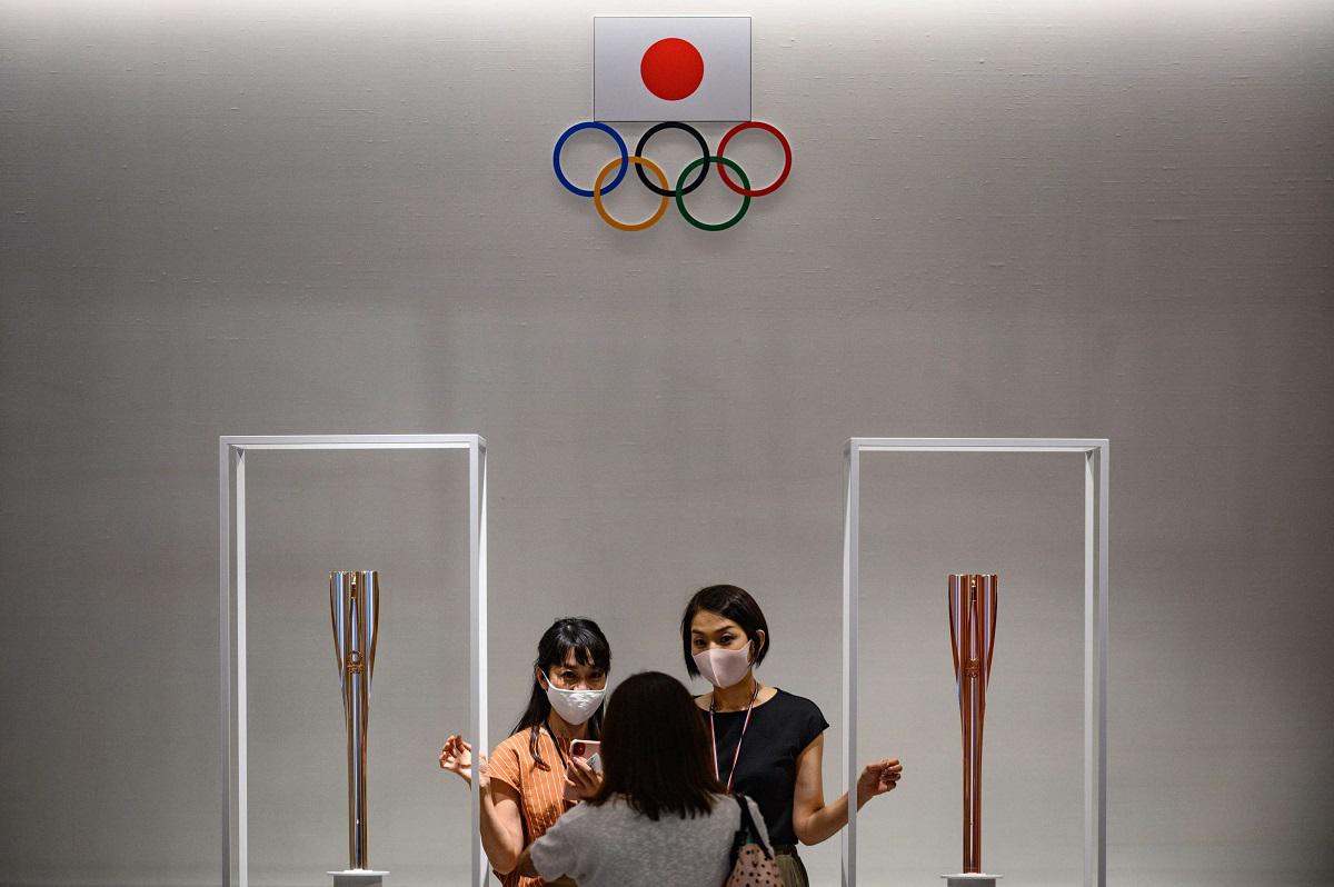  أشخاص يقفون لالتقاط صور مع شعلة أولمبياد طوكيو 2020