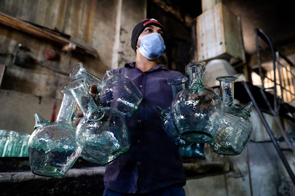 عامل يغسل أباريق في مصنع بطرابلس يقوم بإعادة تدوير الزجاج المكسور نتيجة انفجار بيروت 
