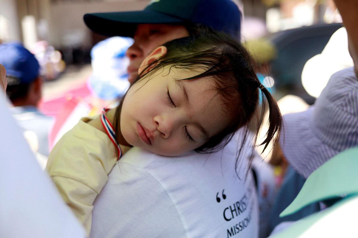 طفلة تايلاندية تنام على كتف والدها