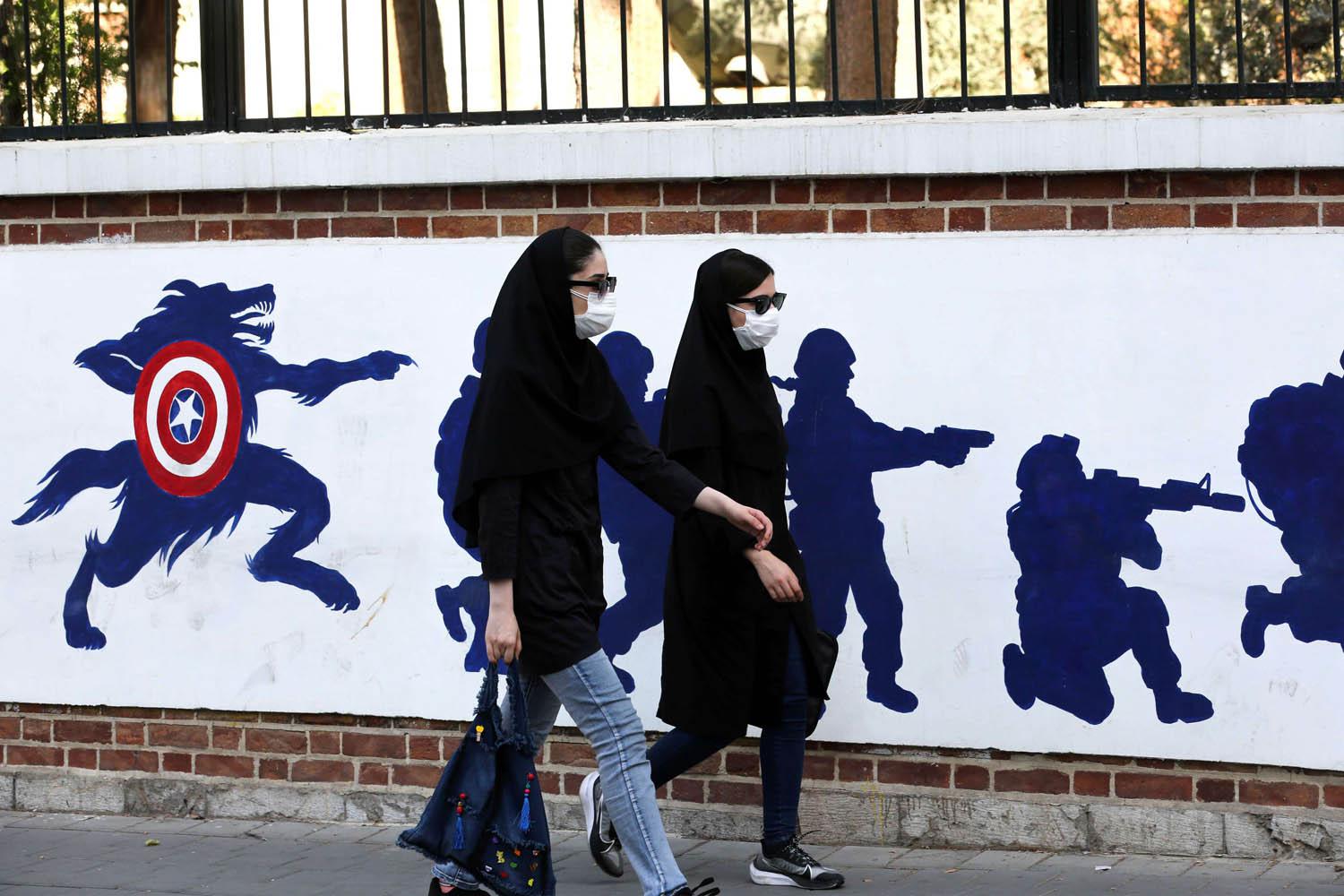 ايرانيات يميشن بالقرب من جدارية عن مواجهة الولايات المتحدة