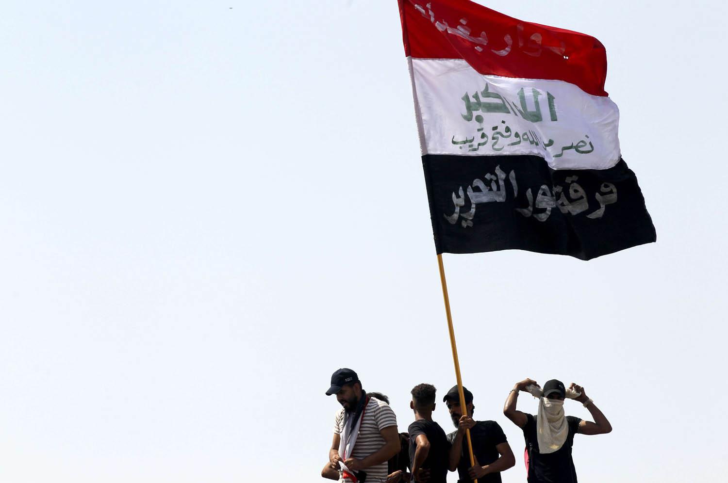 محتجون عراقيون يرفعون علم بلادهم في ساحة التحرير وسط بغداد