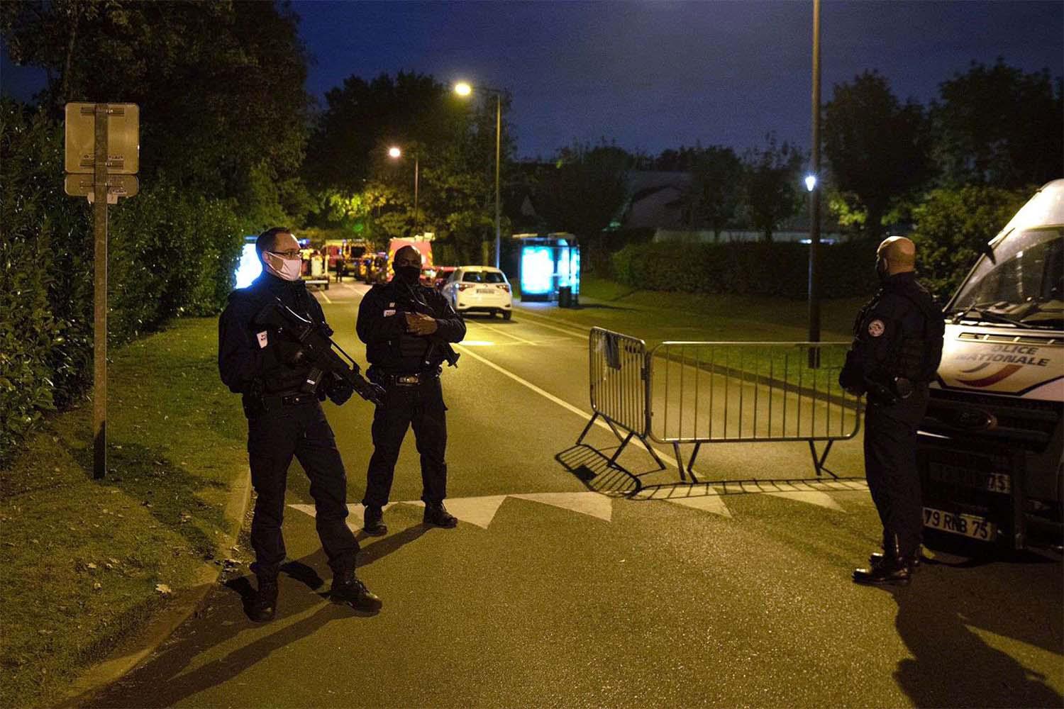 Police officers investigate a crime scene, where a a history teacher was decapitated by an assailant near Paris