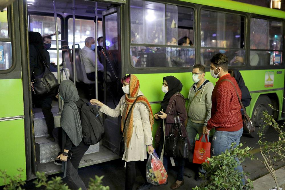 إيرانيون يرتدون أقنعة واقية أثناء ركوبهم حافلة