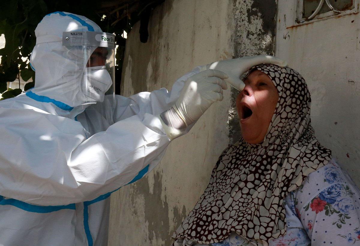 عضو في لجنة التقصي الوبائي يأخذ مسحة من مواطنة في عمان