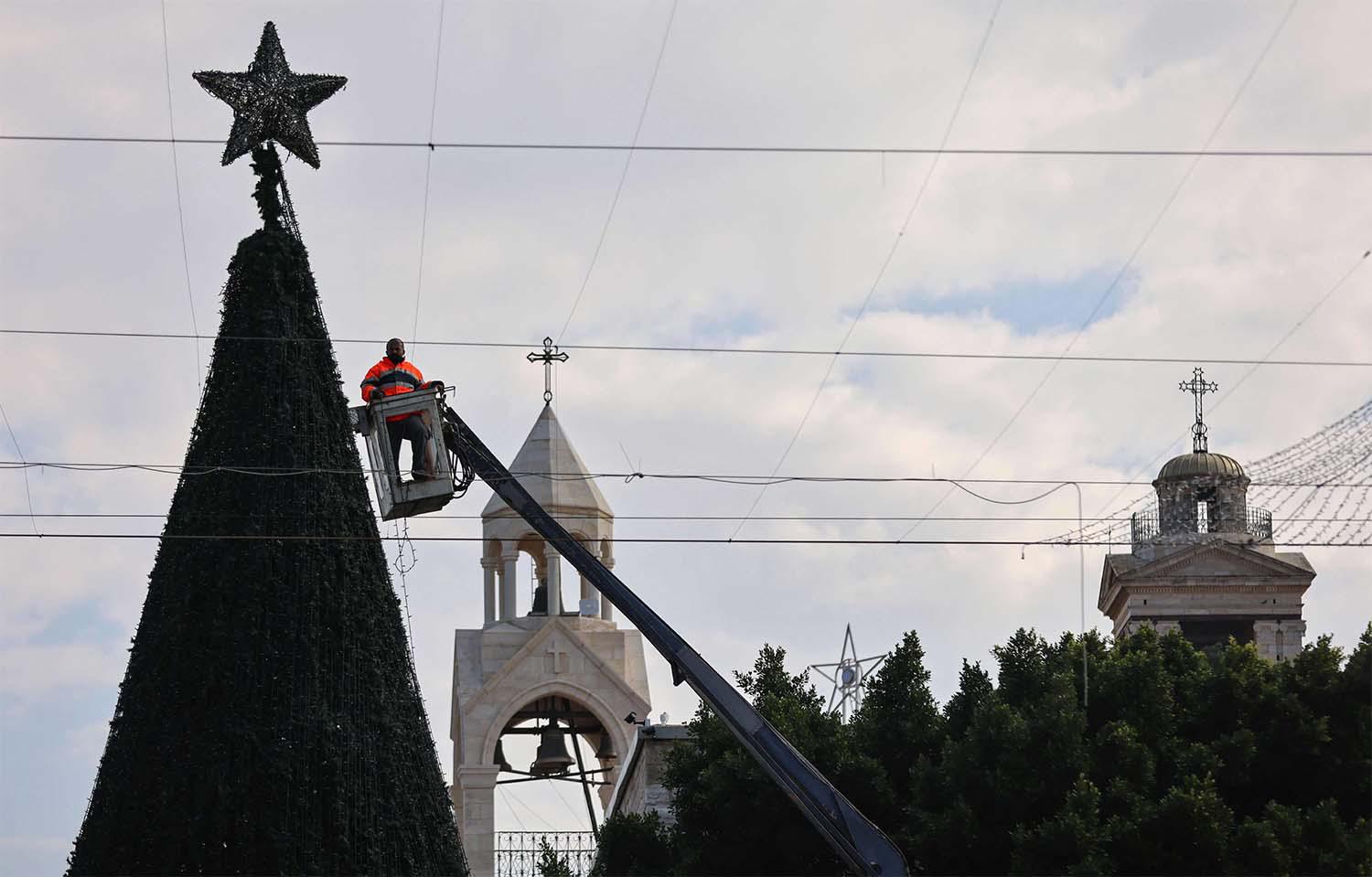 A worker sets up lights on a giant Christmas tree at the Church of the Nativity compound 