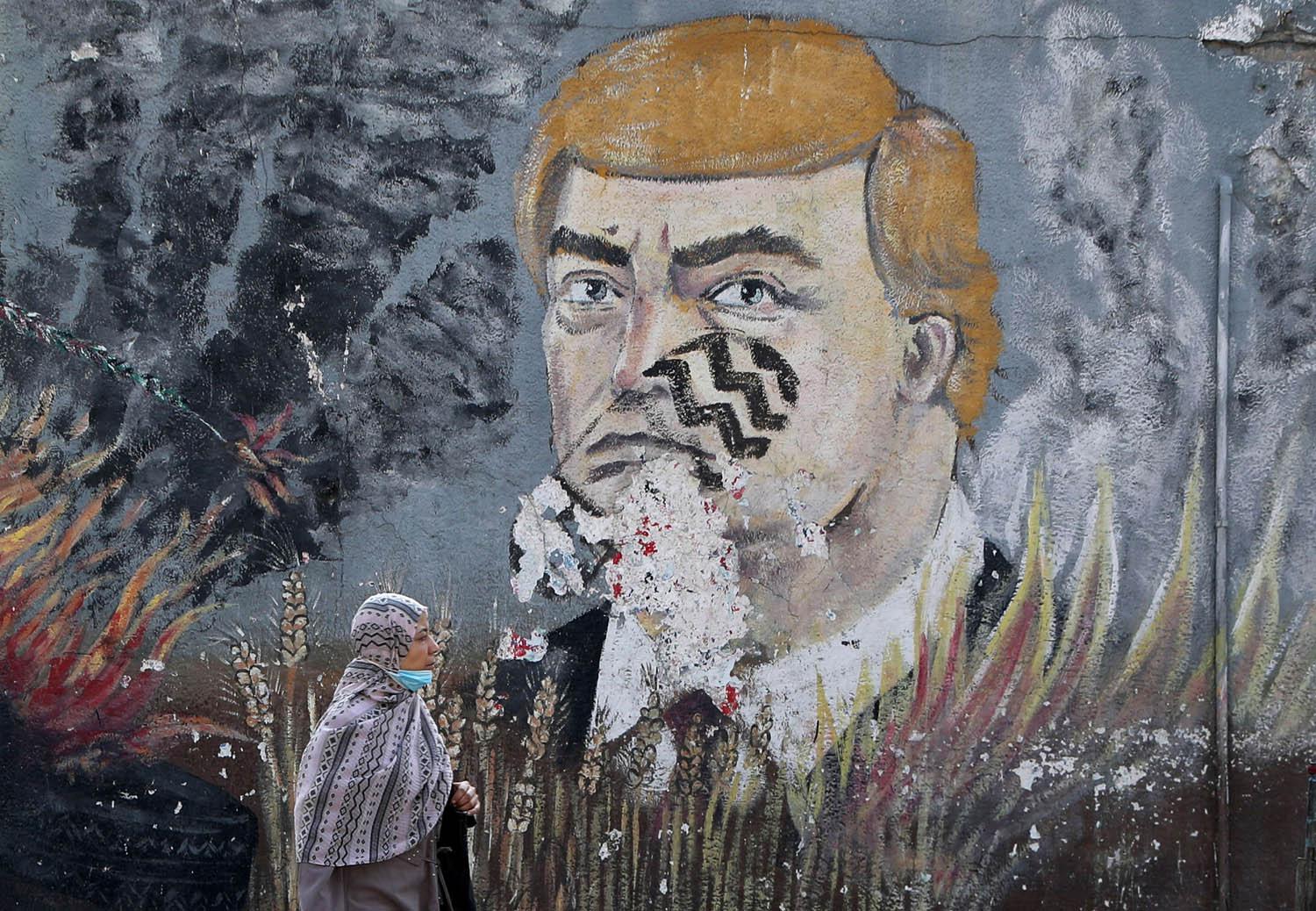 فلسطينية تمر بجانب صورة لترامب مرسومة على جدار في غزة