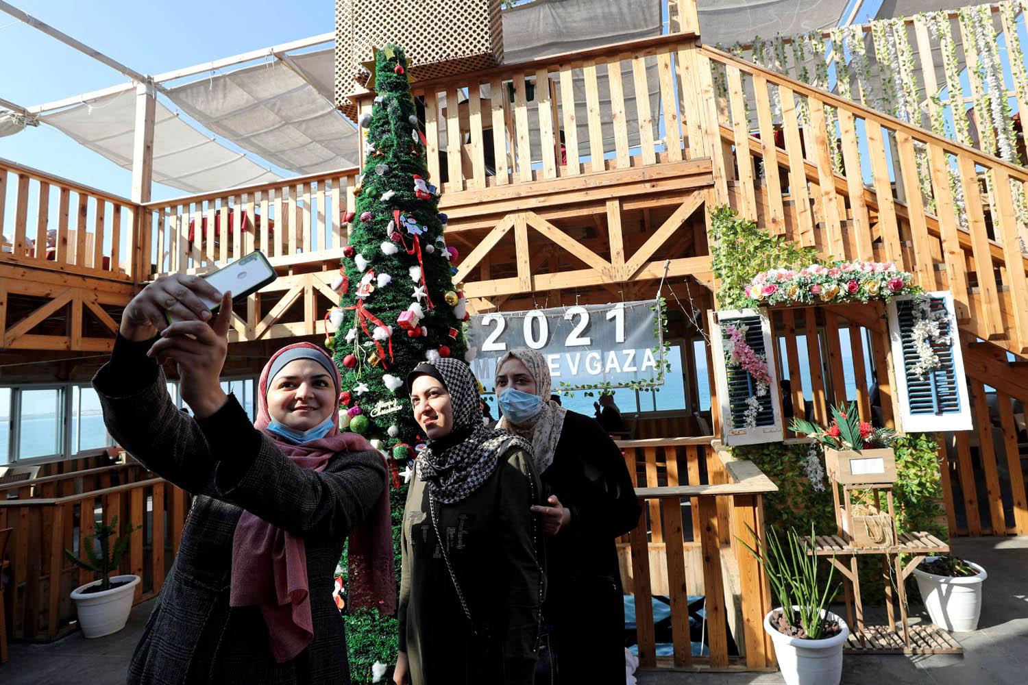 فلسطينيات يصورن انفسهن سيلفي مع شجرة عيد الميلاد في مقهى على ساحل غزة