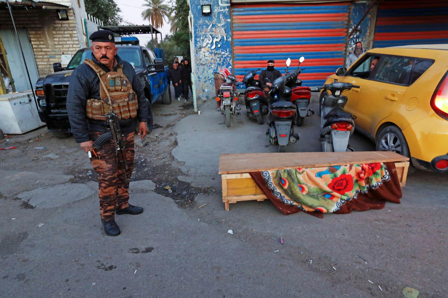 شرطي عراقي بجانب تابوت لضحية من ضحايا تفجير ساحة الطيران في بغداد