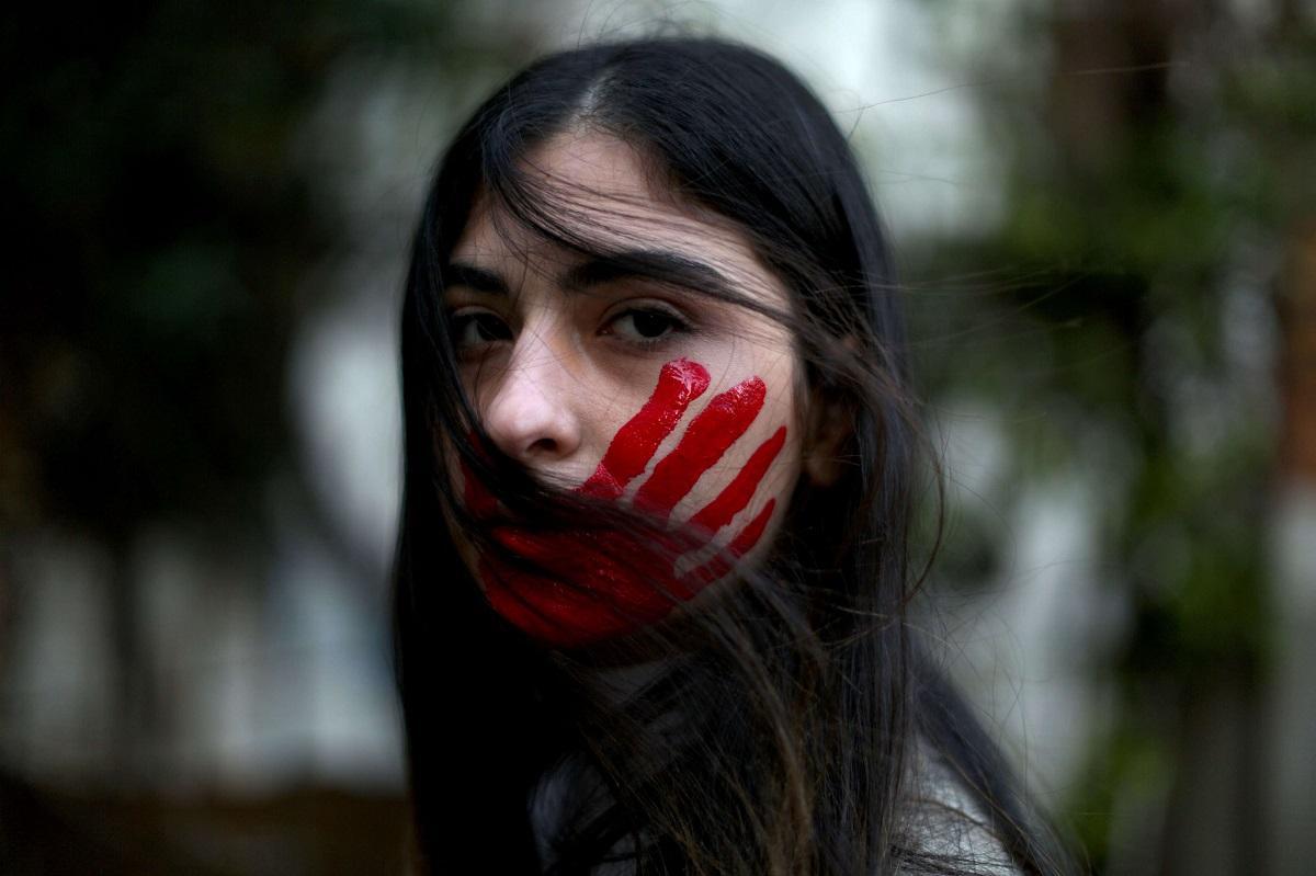 امرأة اميركية ترسم على وجهها ضربة كف بالاحمر احتجاجا على العنف ضد النساء
