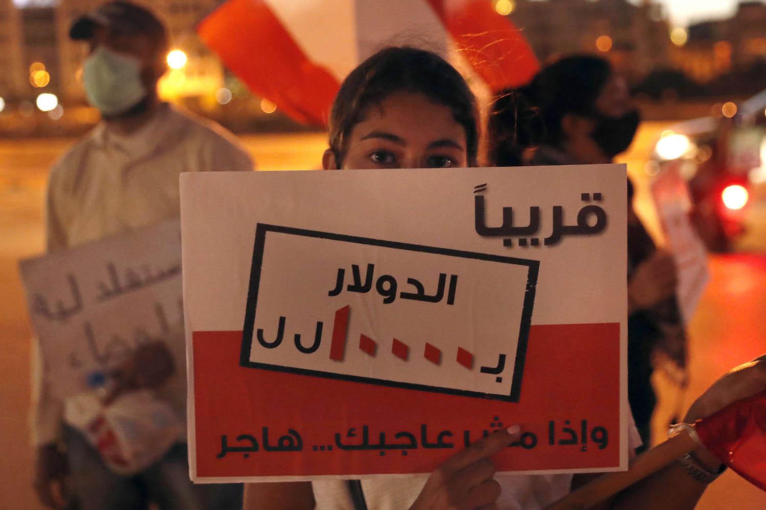 طفل لبناني يرفع لافتة تحذر من انهيار العملة