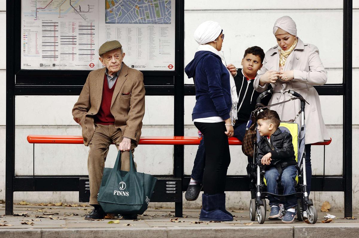 رجل وحيد يجلس بجوار عائلة في محطة للحافلات في لندن