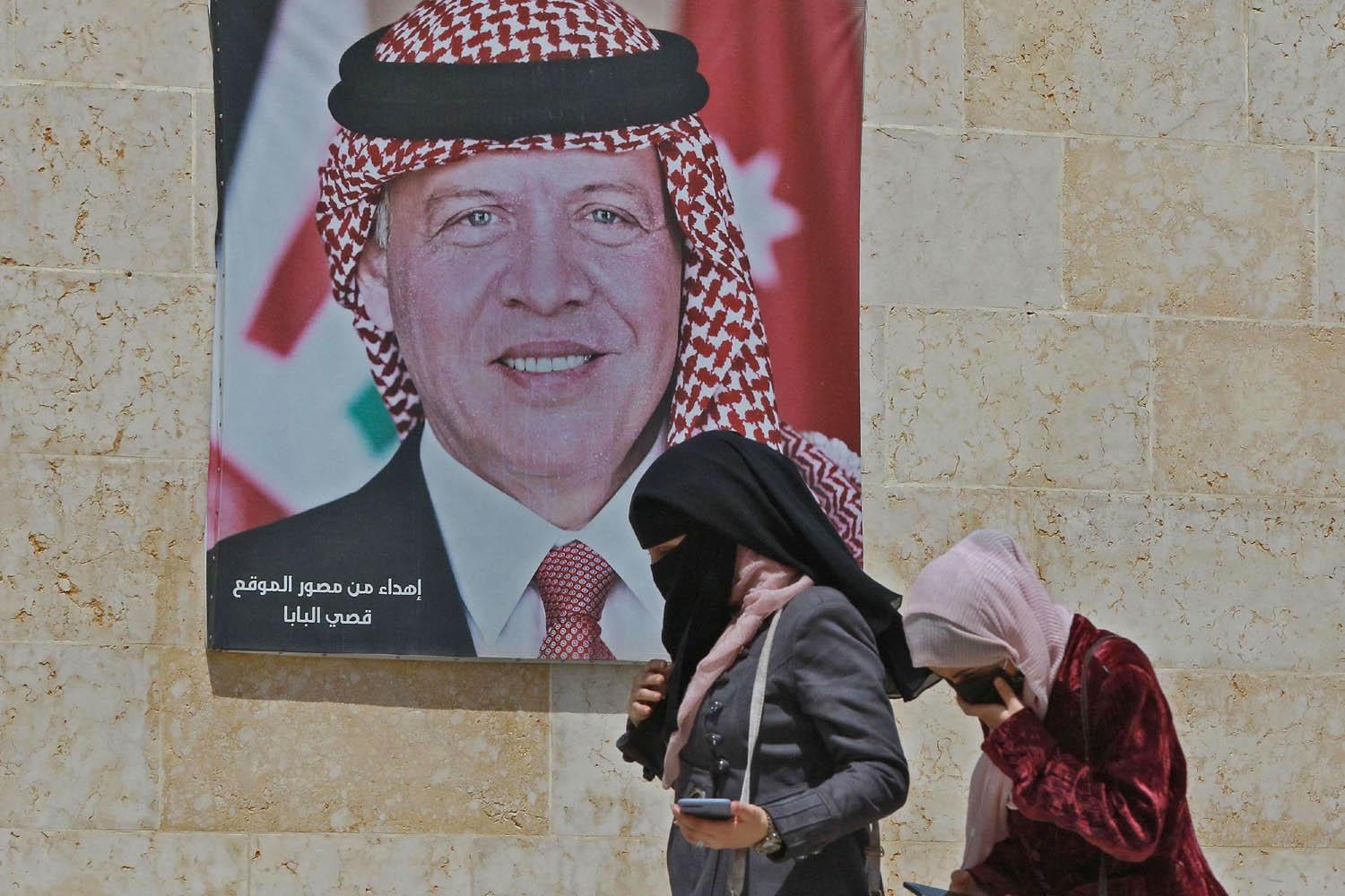 اردنيات يمررن بجانب صورة جدارية للعاهل الأردني الملك عبدالله الثاني
