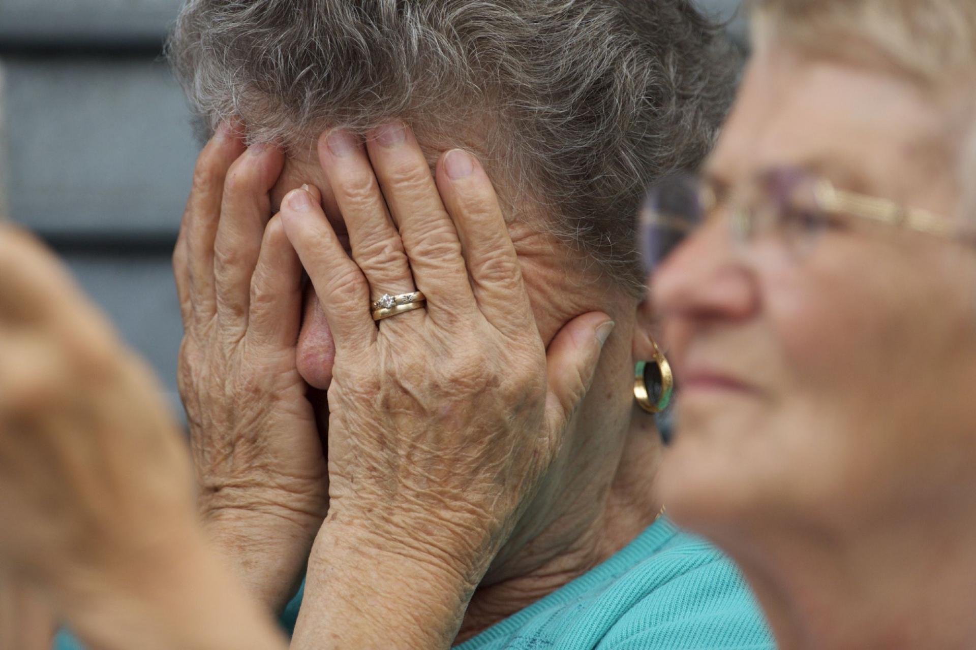 سيدة أميركية مسنة تضع يديها على رأسها خلال قداس دفن مسيحي