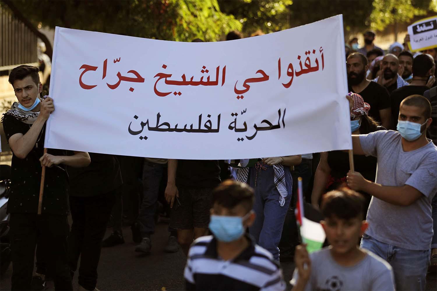 Protesters carry an Arabic banner that reads: "Save the Sheikh Jarrah neighborhood, Freedom for Palestine"