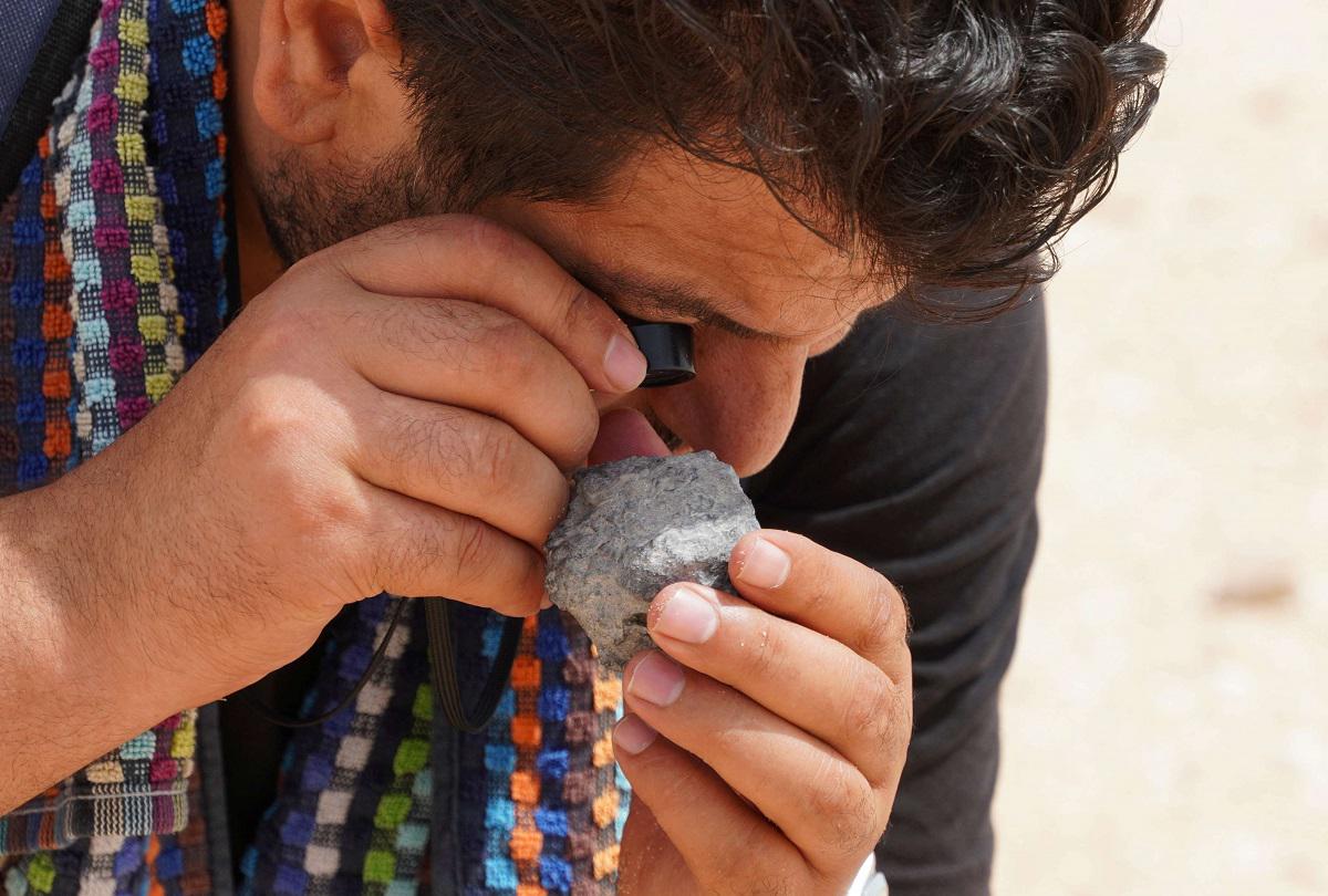 صياد النيازك علي المغاري يتفقد حجرًا بالقرب من قرية تامري في المغرب
