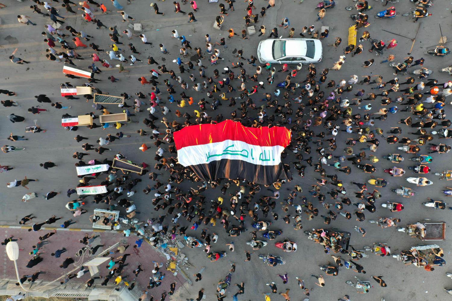 عراقيون يحملون علما عراقيا وتوابيت فارغة يتظاهرون وسط بغداد