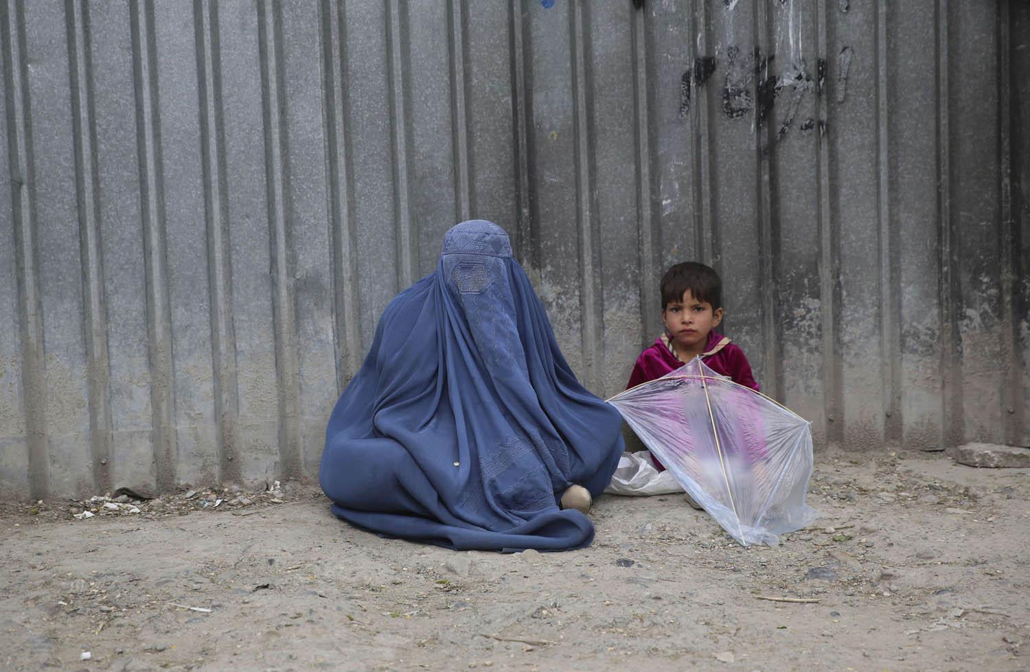 أفغانية وابنها عند سور أمني وسط كابول