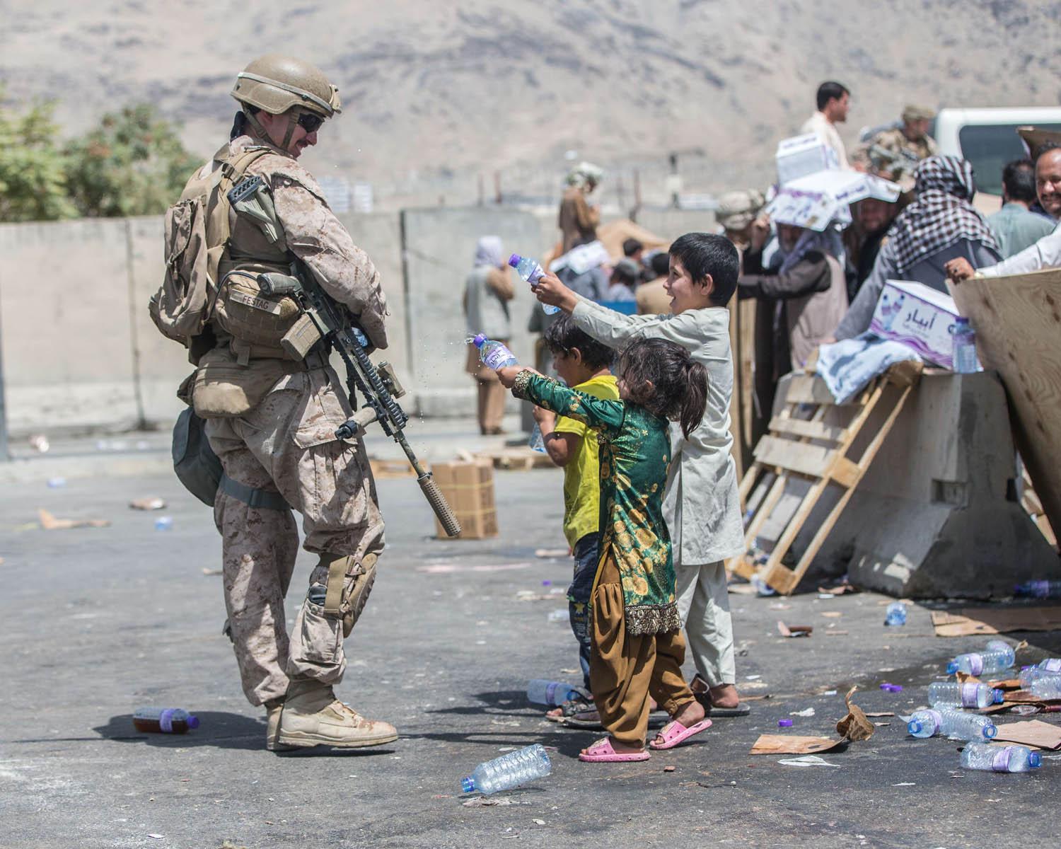 اطفال افغان يعرضون قوارير الماء على جندي أميركي