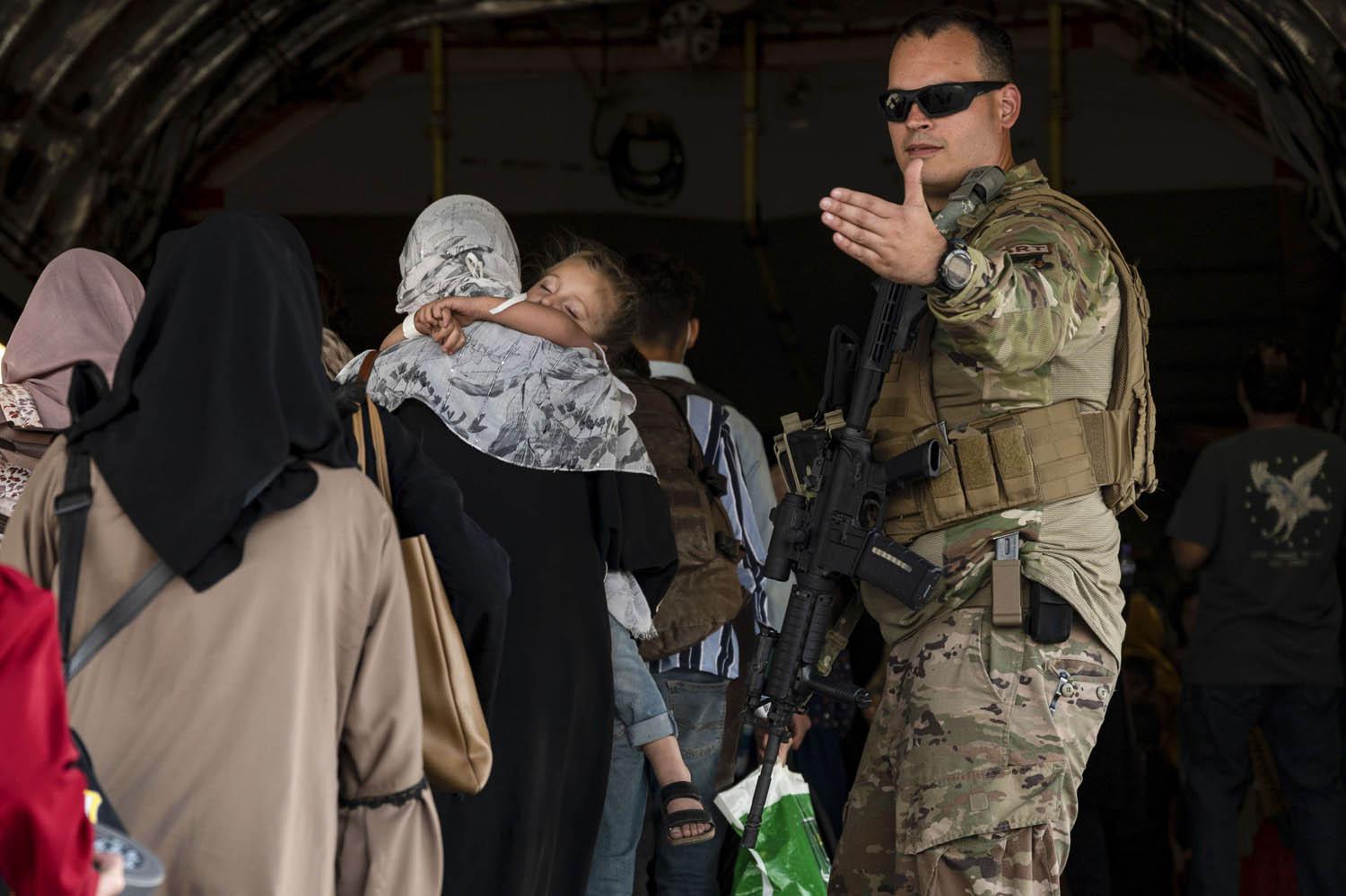 جندي أميركي يوجه لاجئين أفغان للصعود في طائرة عسكرية