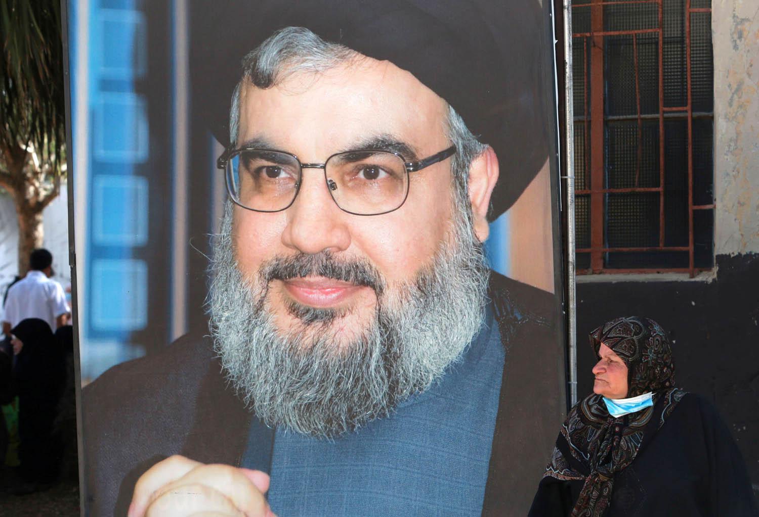 لبنانية تجلس بالقرب من جدارية لحسن نصرالله