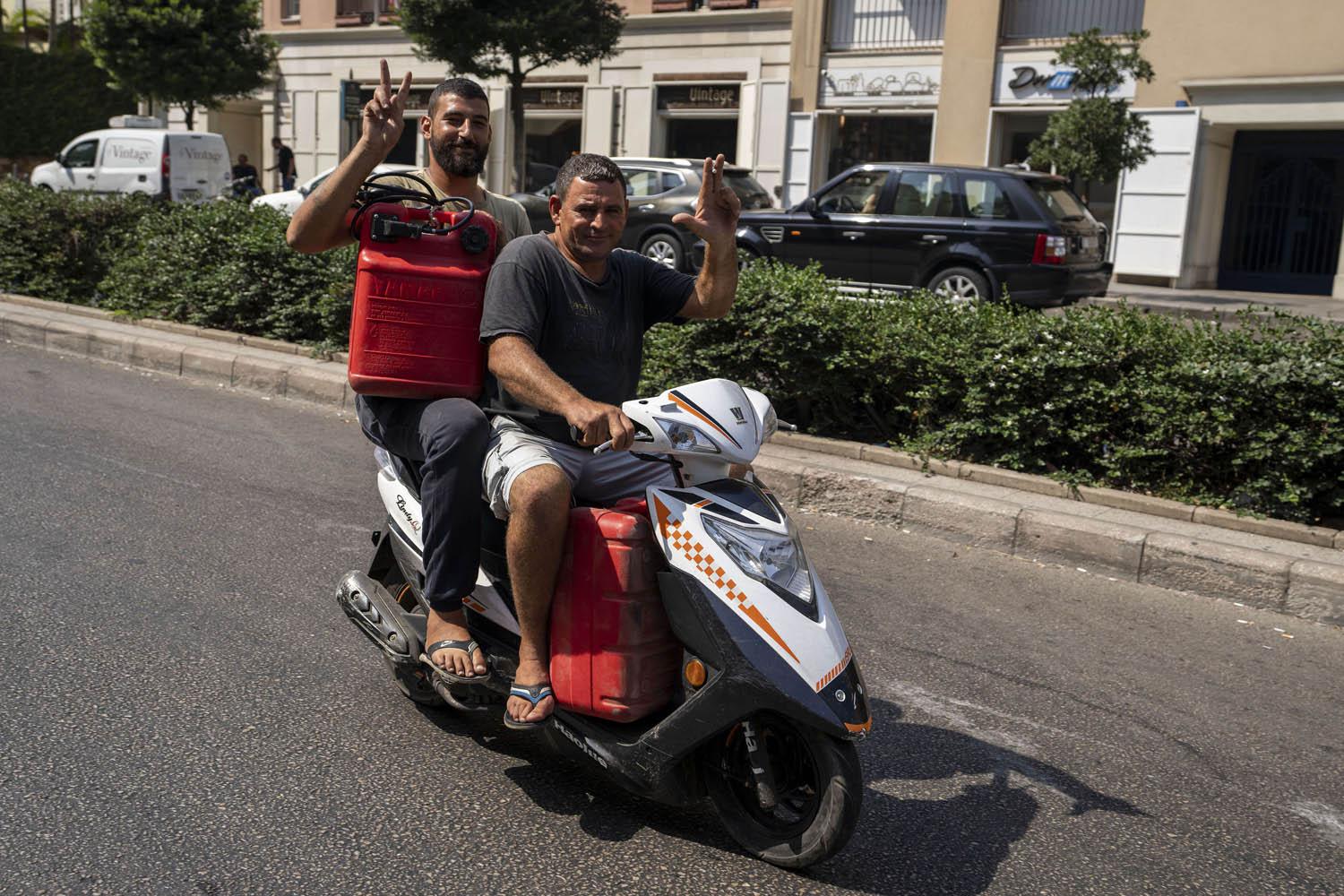 صيادان لبنانيان على دراجة نارية يحملان وقودا لقاربهما