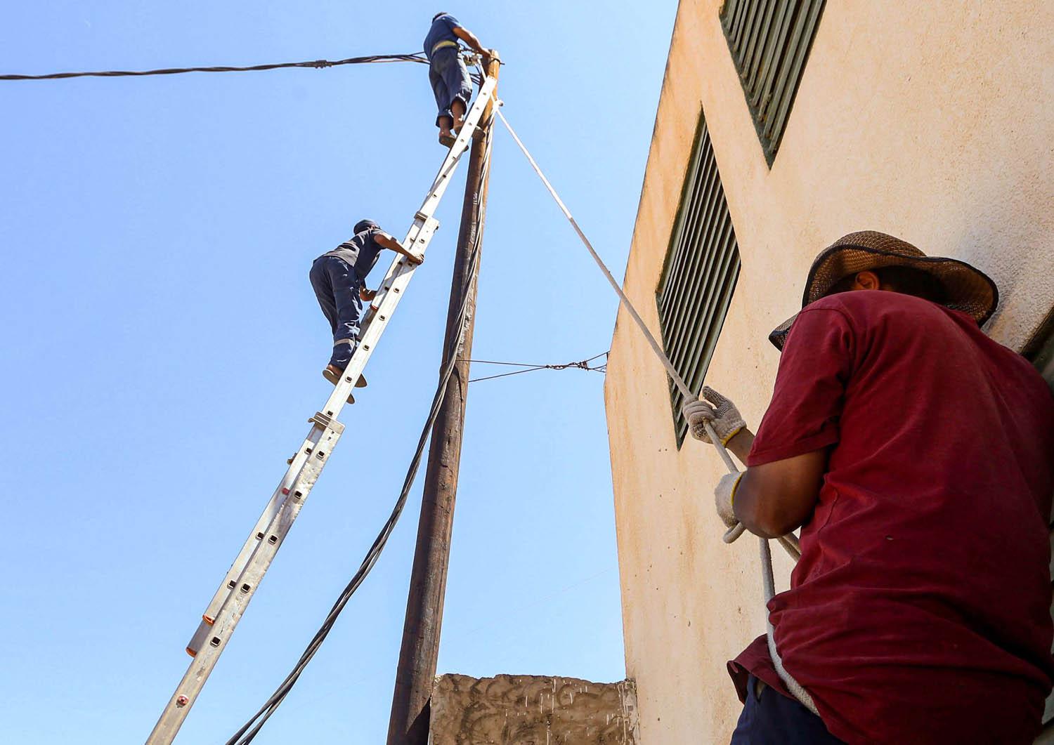 عمال ليبيون يصلحون خط كهرباء في طرابلس