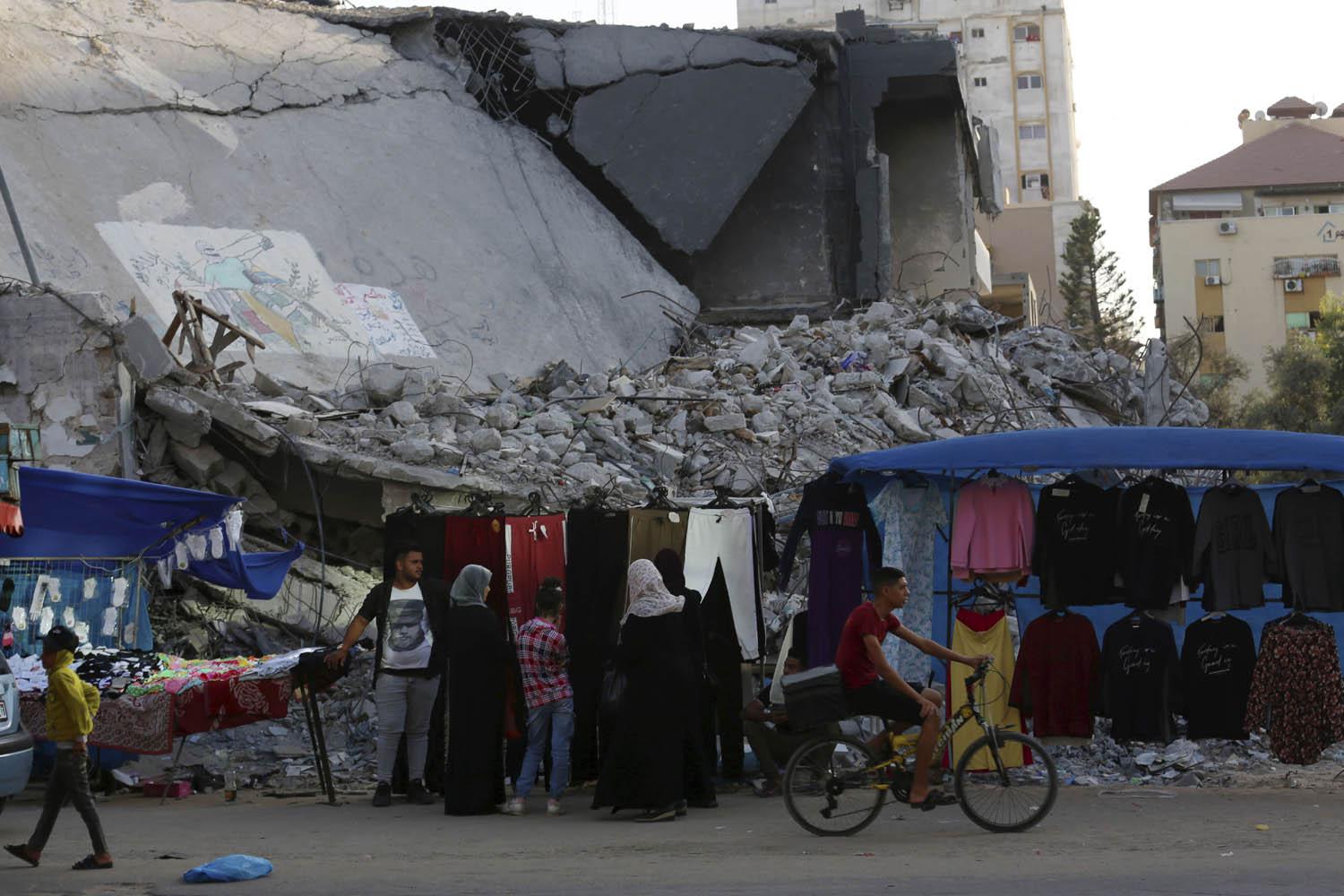 نساء فلسطينيات في سوق أمام مبنى مدمر في غزة