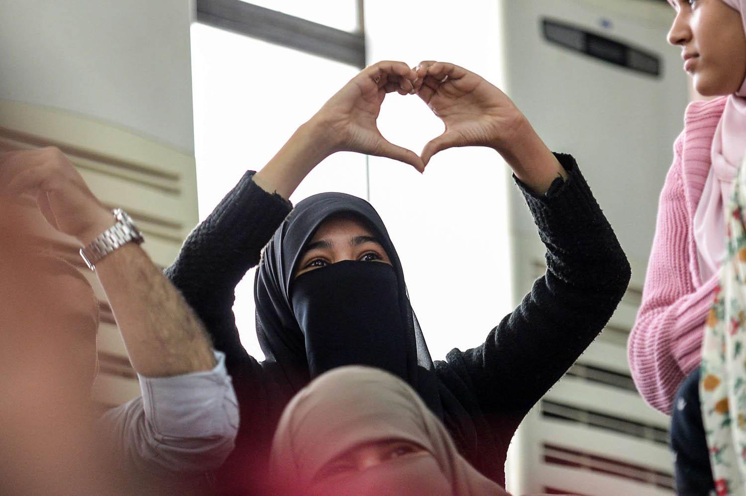 مصرية ترسم شارة الحب في محاكمة أعضاء في جماعة الأخوان في القاهرة