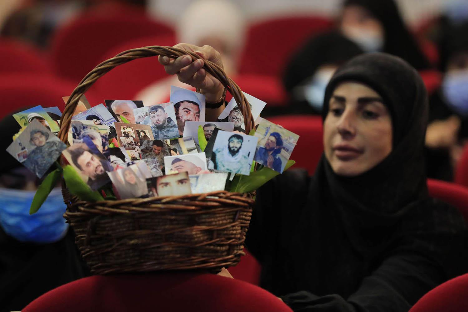 ناشطة في حزب الله تحمل سلة بصور لمقاتلين لبنانيين وايرانيين قتلى