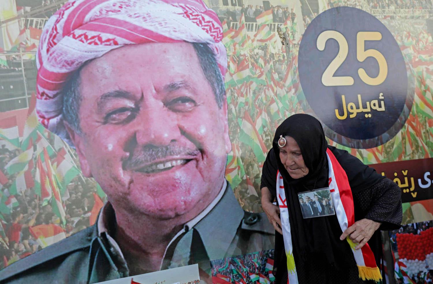 كردية تمر بجانب جدارية للزعيم الكردي مسعود بارزاني