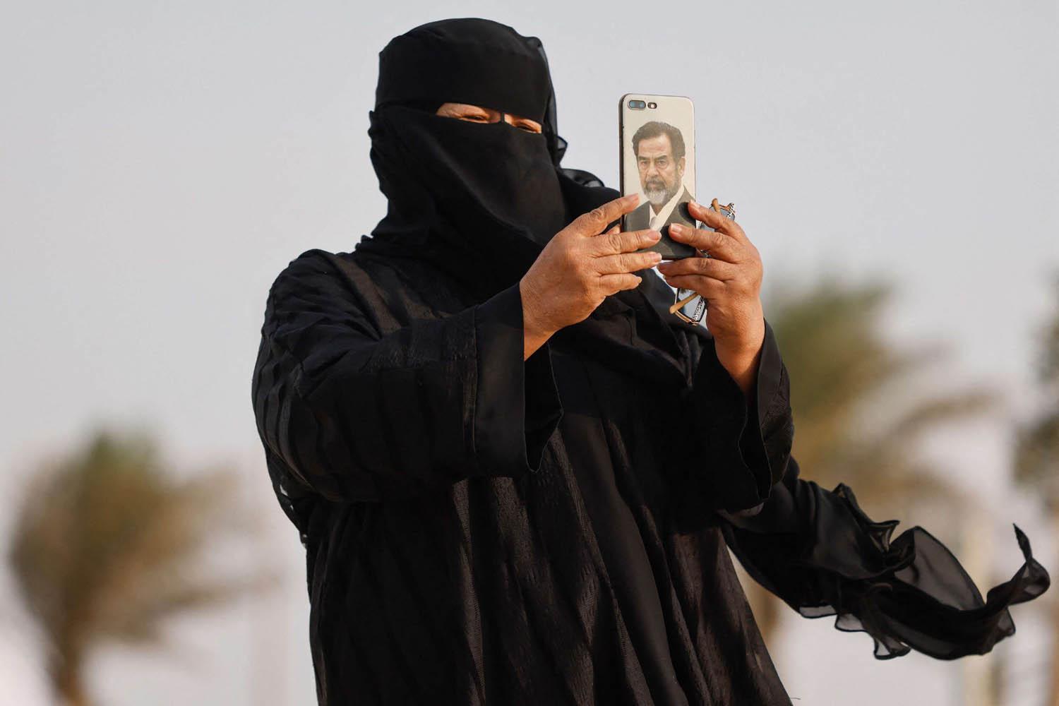 قطرية تأخذ صورة خلال المونديال بموبايل عليه صورة الرئيس العراقي الراحل صدام حسين