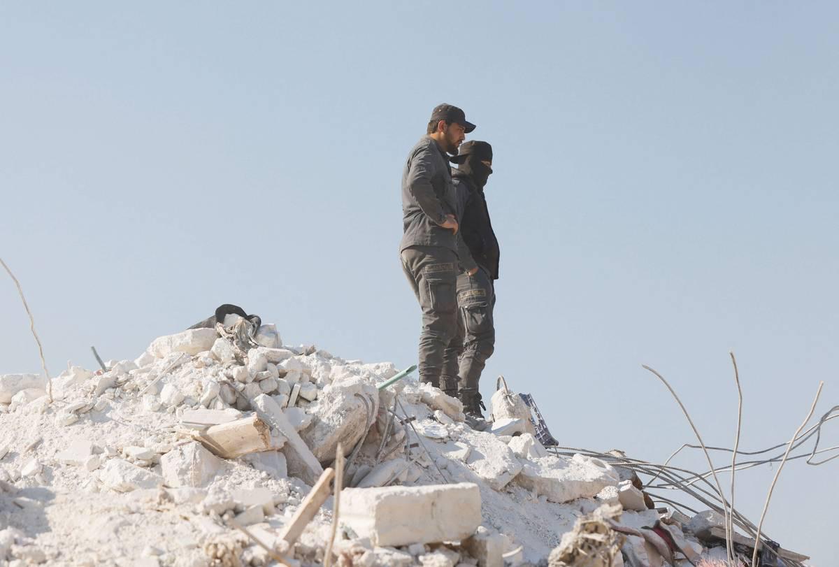 سوريان يقفان على مبنى منهار في ادلب شمال سوريا