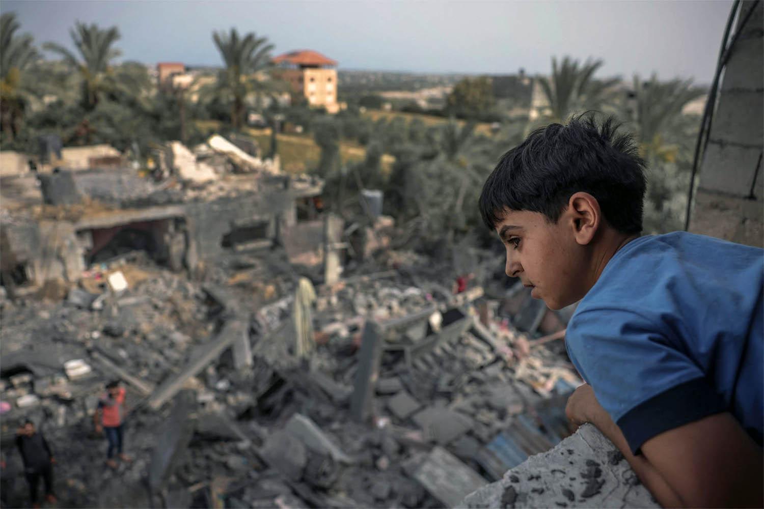 A child watches from a window as people sift through the rubble of a building hit in an Israeli air strike in Biet Hanoun