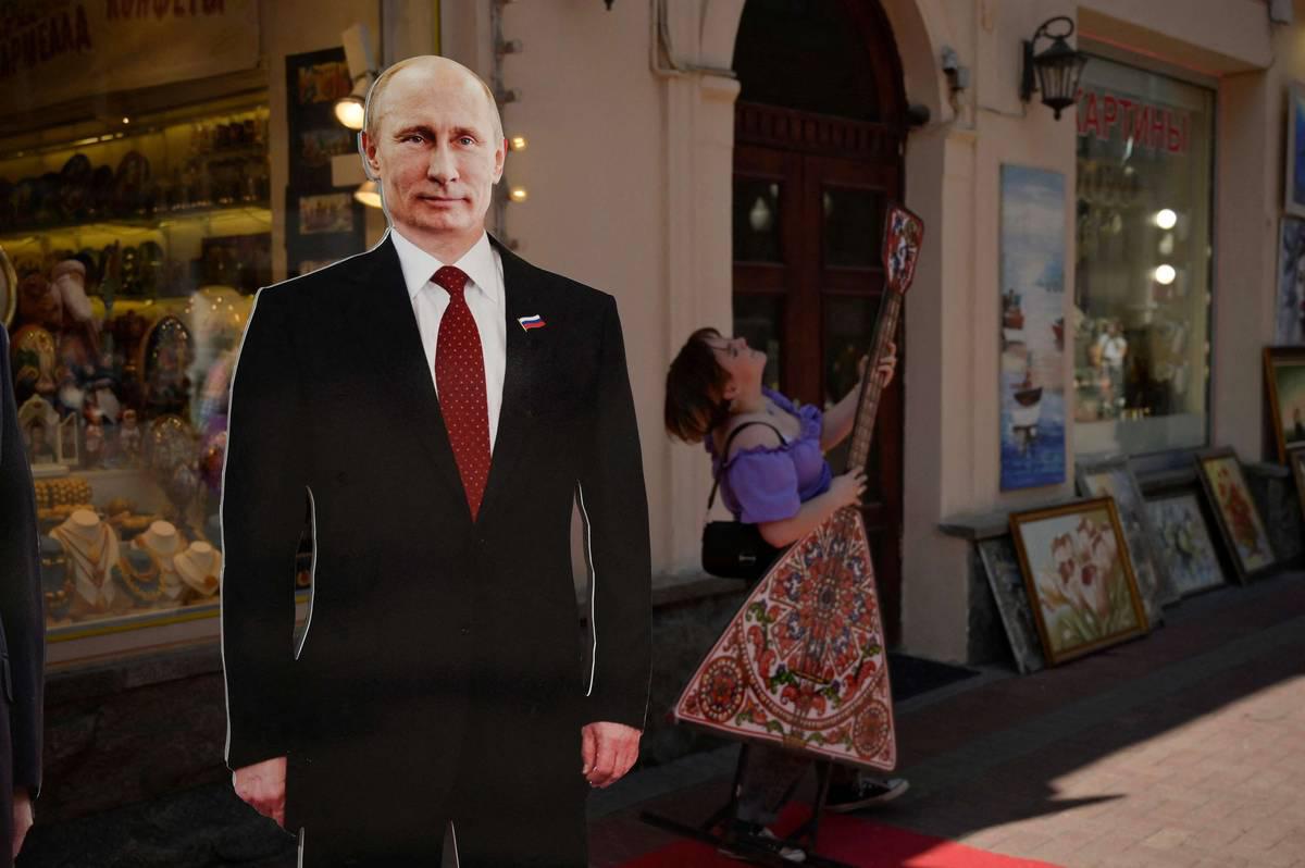 روسية تعزف بالقرب لصورة للرئيس بوتين