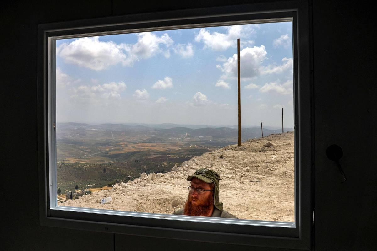 إسرائيلي يطل على مبنى في مستعمرة في الضفة