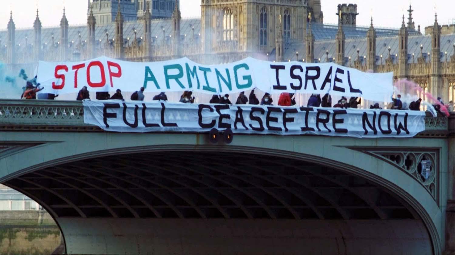 Pro-Palestinian activists unflur banners calling on the British government to demand a full ceasefire in Gaza