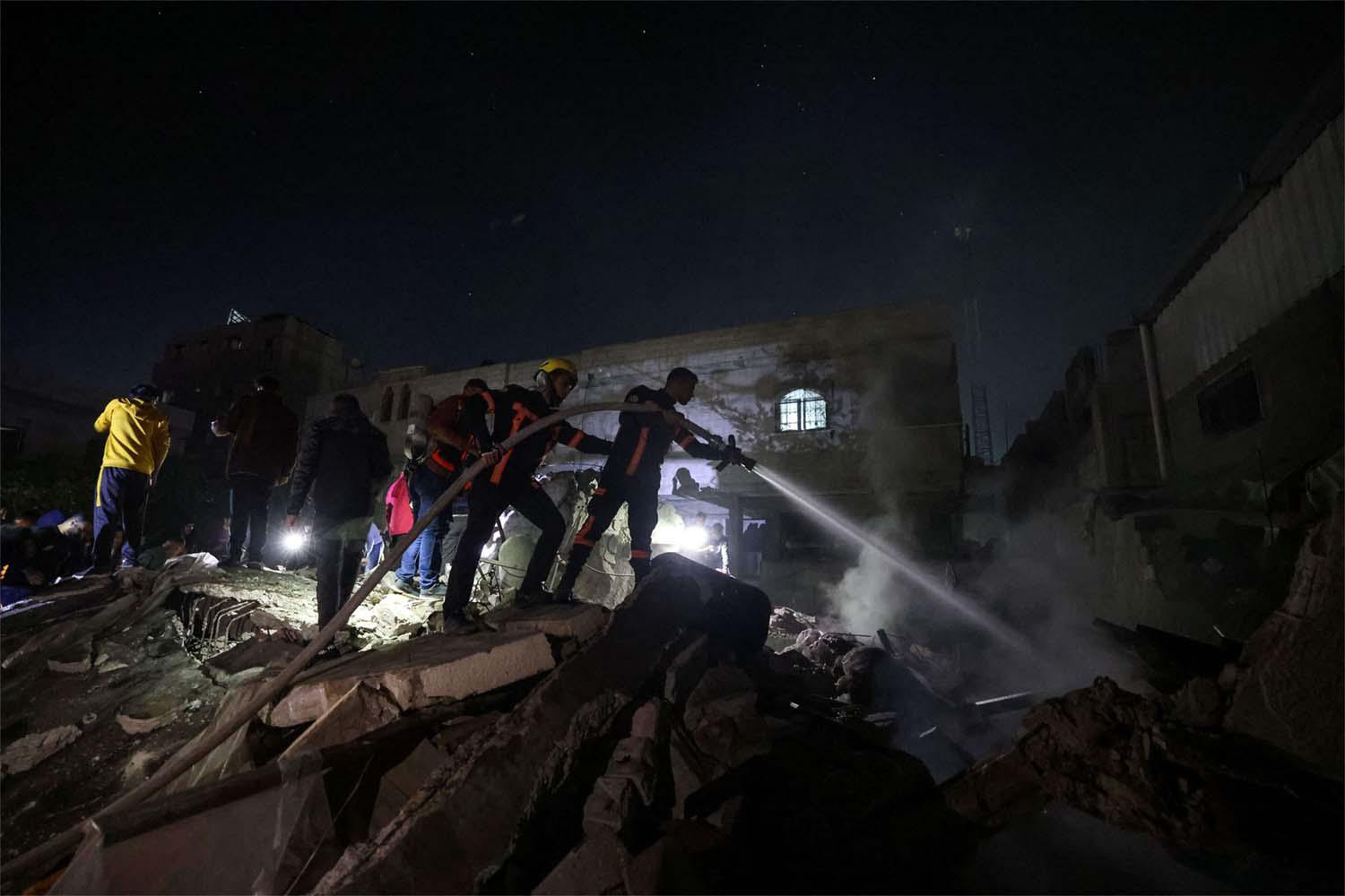 Firefighters spray water on the rubble of a building following Israeli bombardment in Rafah