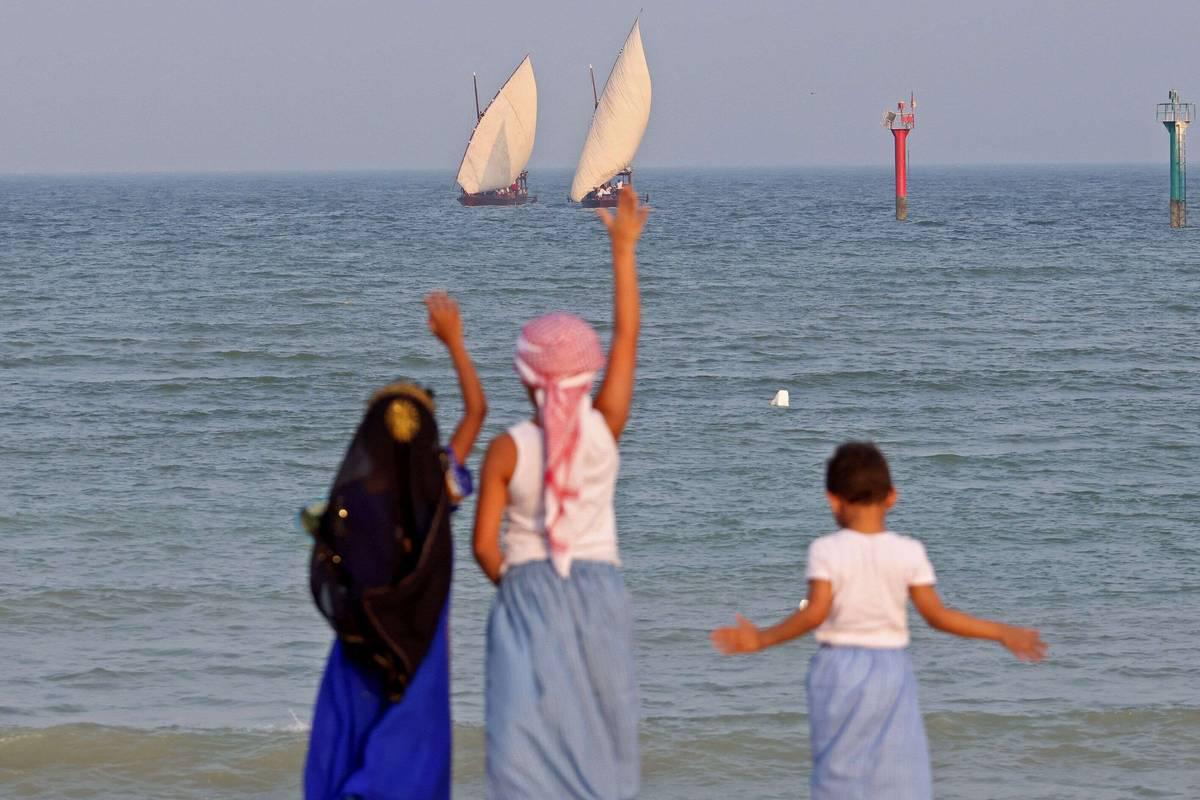 أطفال كويتيون يلوحون لسفن في مدينة الكويت