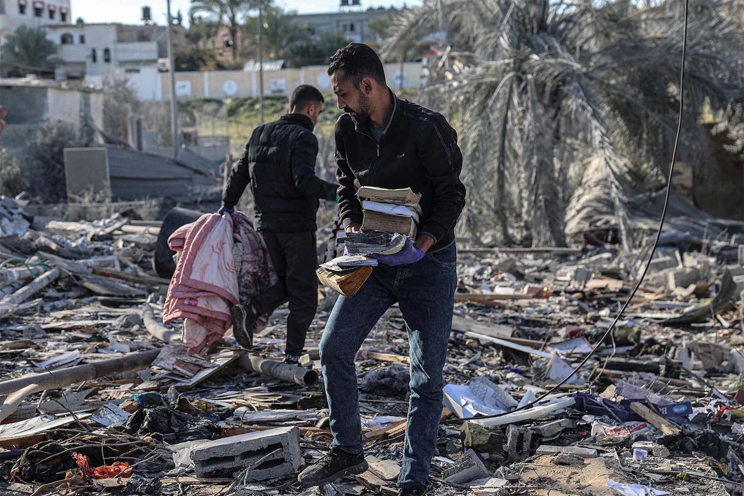 Palestinians search for their belongings amid the rubble of houses destroyed by Israeli bombardment in Rafah