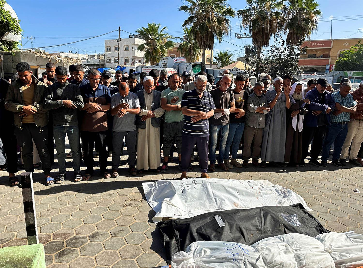Mourners pray next to the bodies of Palestinians killed in an Israeli strike