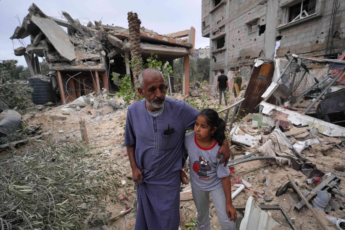 فلسطينيون عند ركام مبان دمرها القصف في غزة
