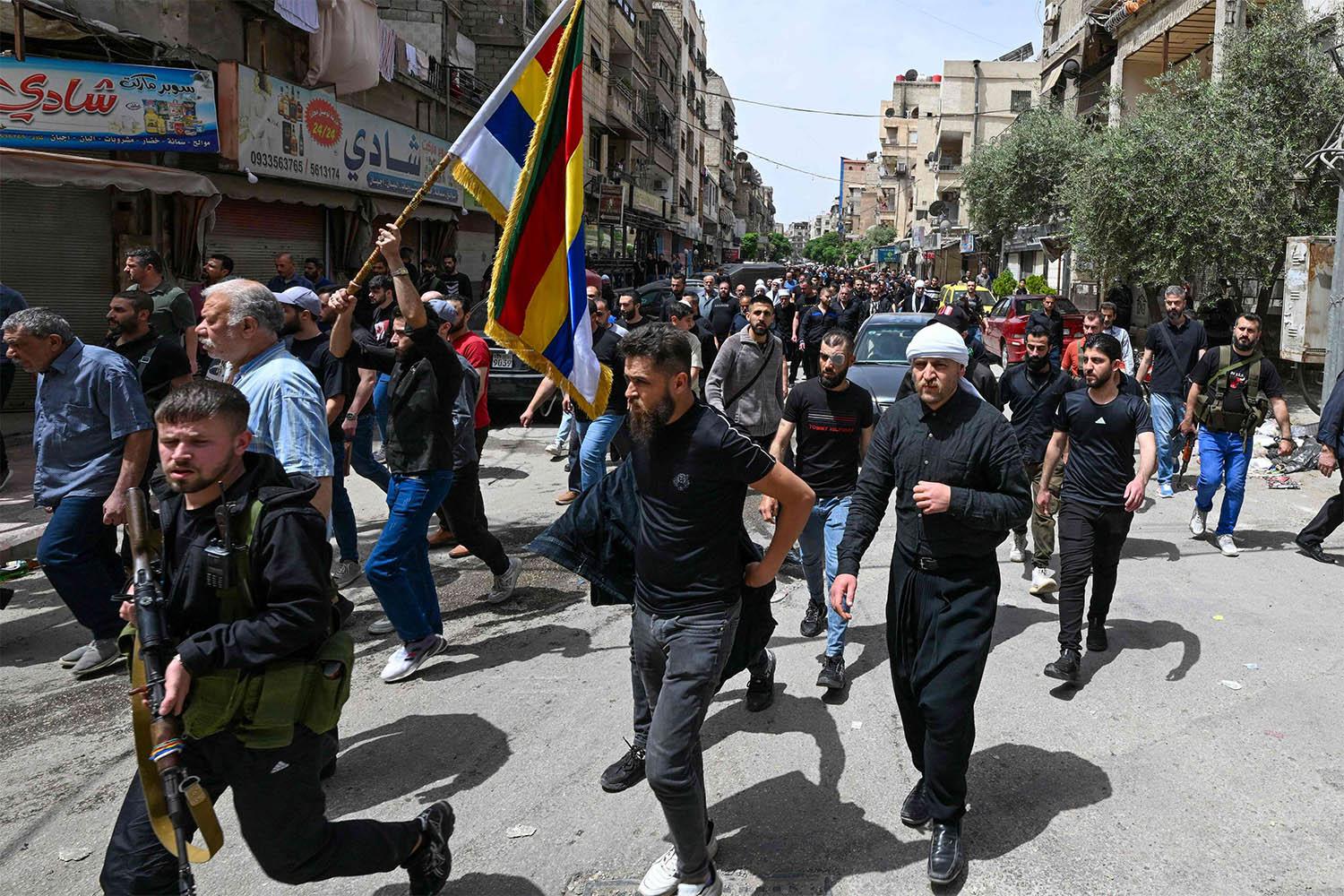 Armed members of Syria's Druze community attend the funeral of seven people killed during overnight clashes with Syrian security forces, in Damascus