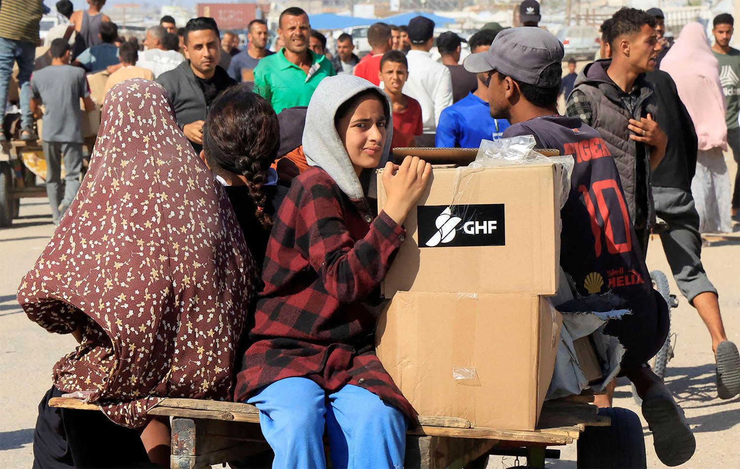 People ride a cart as Palestinians seeking aid gather near an aid distribution site run by the US-backed Gaza Humanitarian Foundation in Rafah