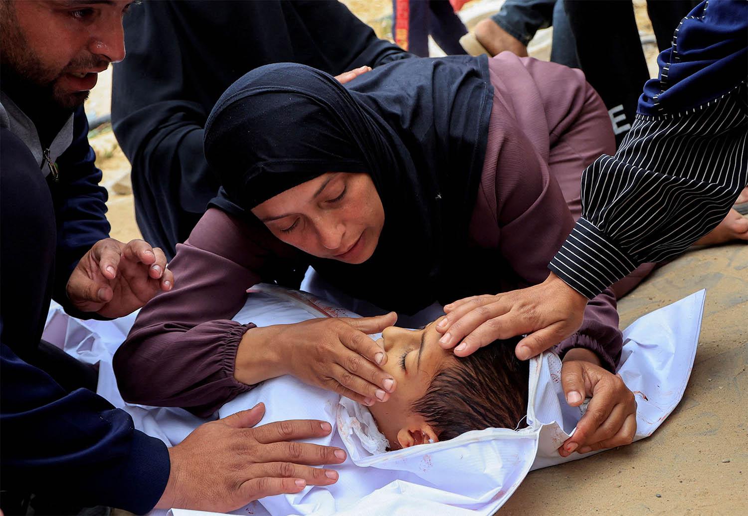 Mourners react as they look at the body of a Palestinian boy killed in an Israeli strike